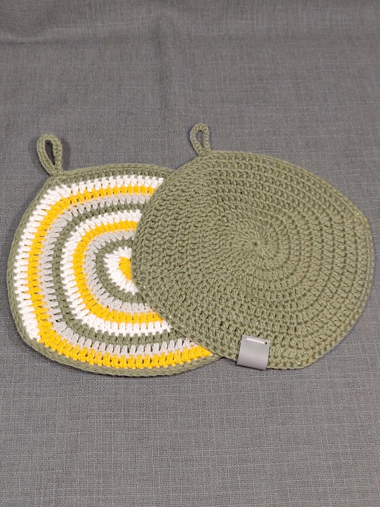 Handgehäkelte Topflappen mit buntem Spiralmuster und einfarbig grüner Rückseite