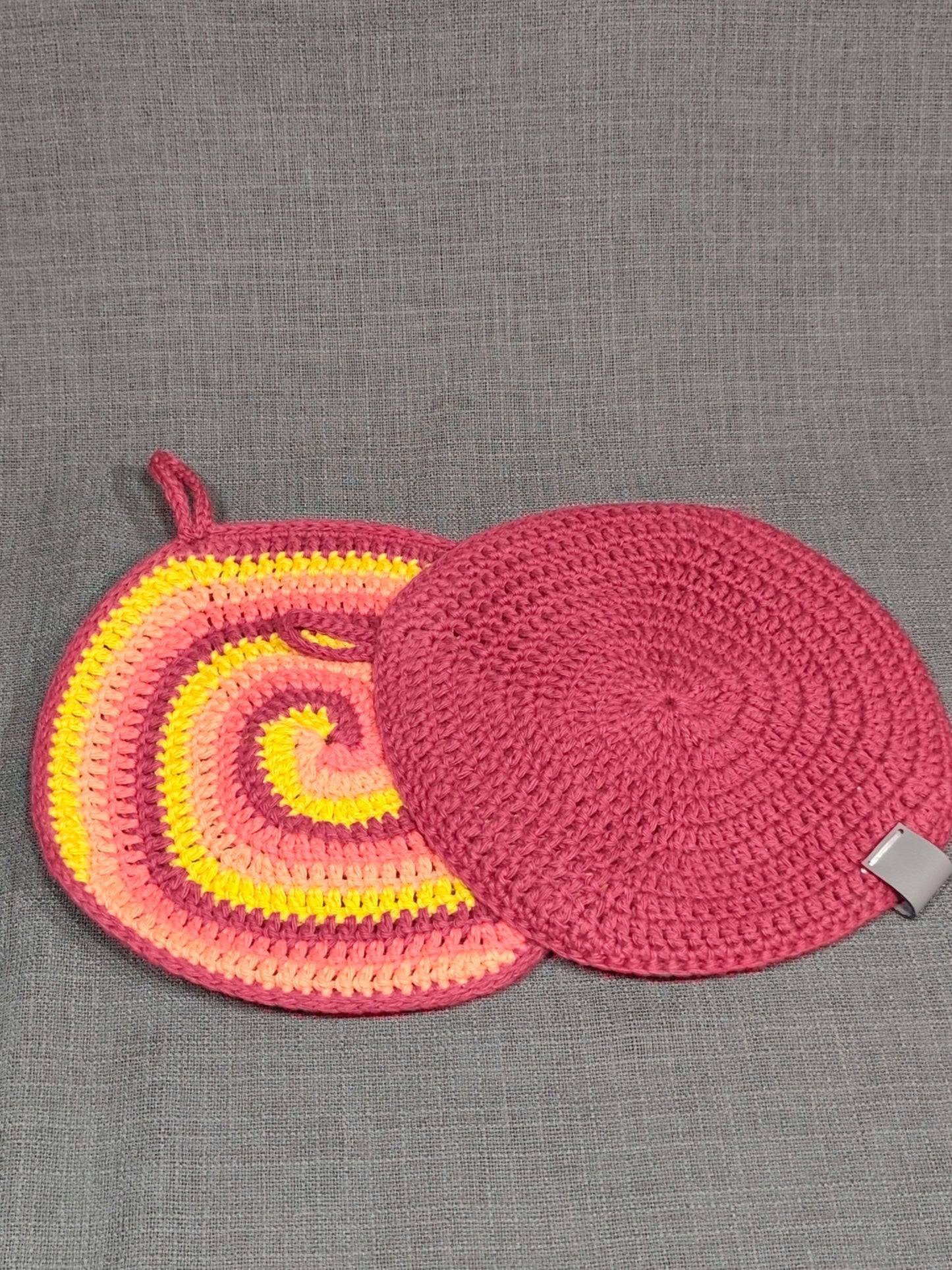 Gehäkelte Topflappen mit buntem Spiralmuster und einfarbig dunkelroter Rückseite